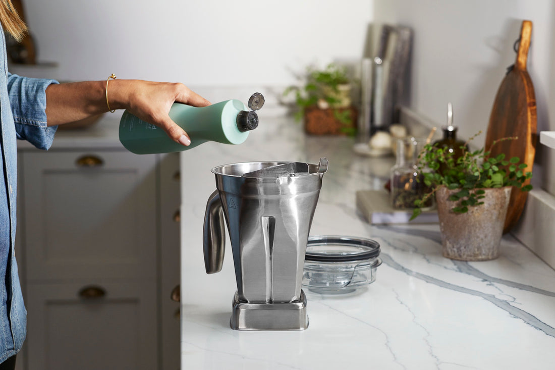 Spülmittel wird in einen Vitamix-Behälter gegeben, der Deckel liegt daneben auf der Arbeitsplatte