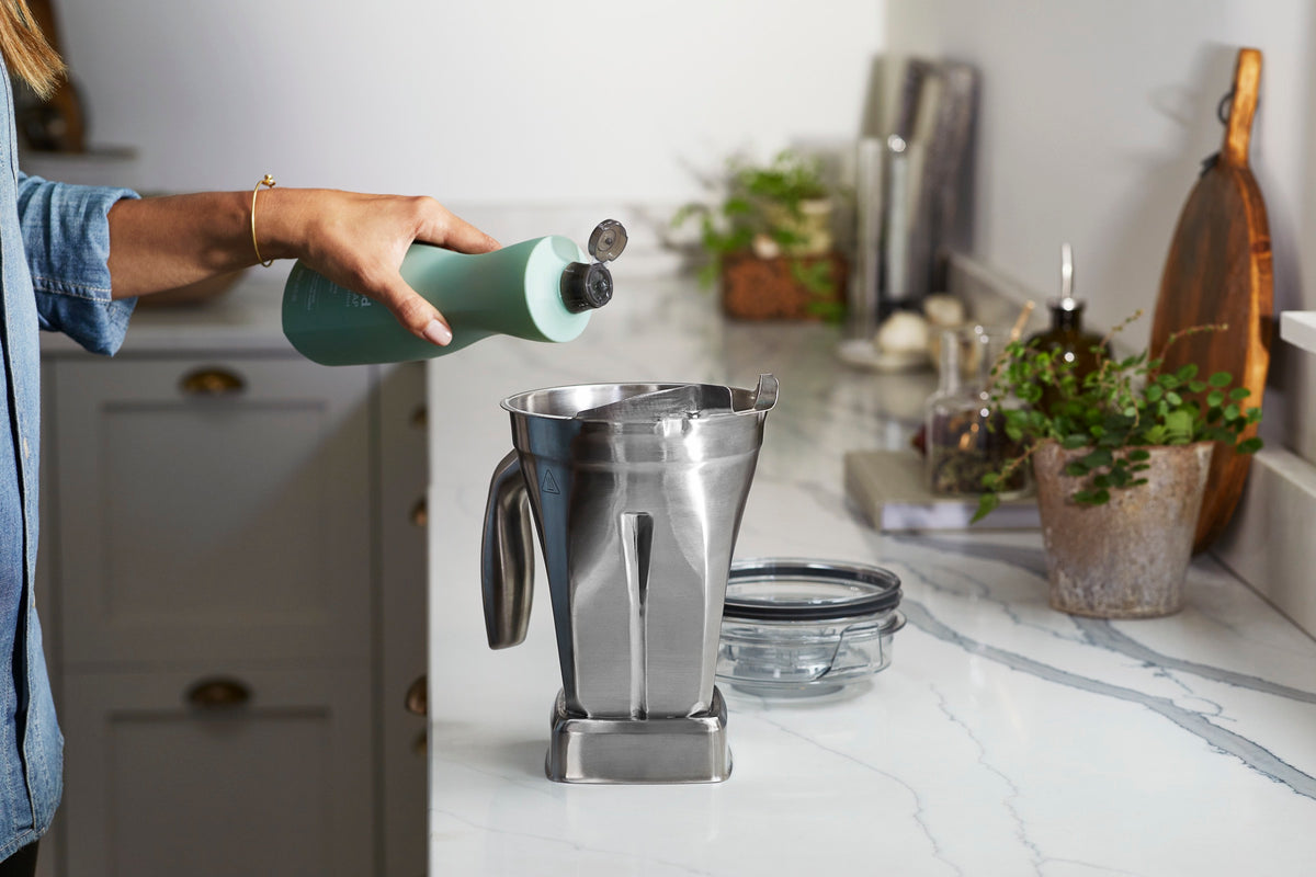Spülmittel wird in einen Vitamix-Behälter gegeben, der Deckel liegt daneben auf der Arbeitsplatte