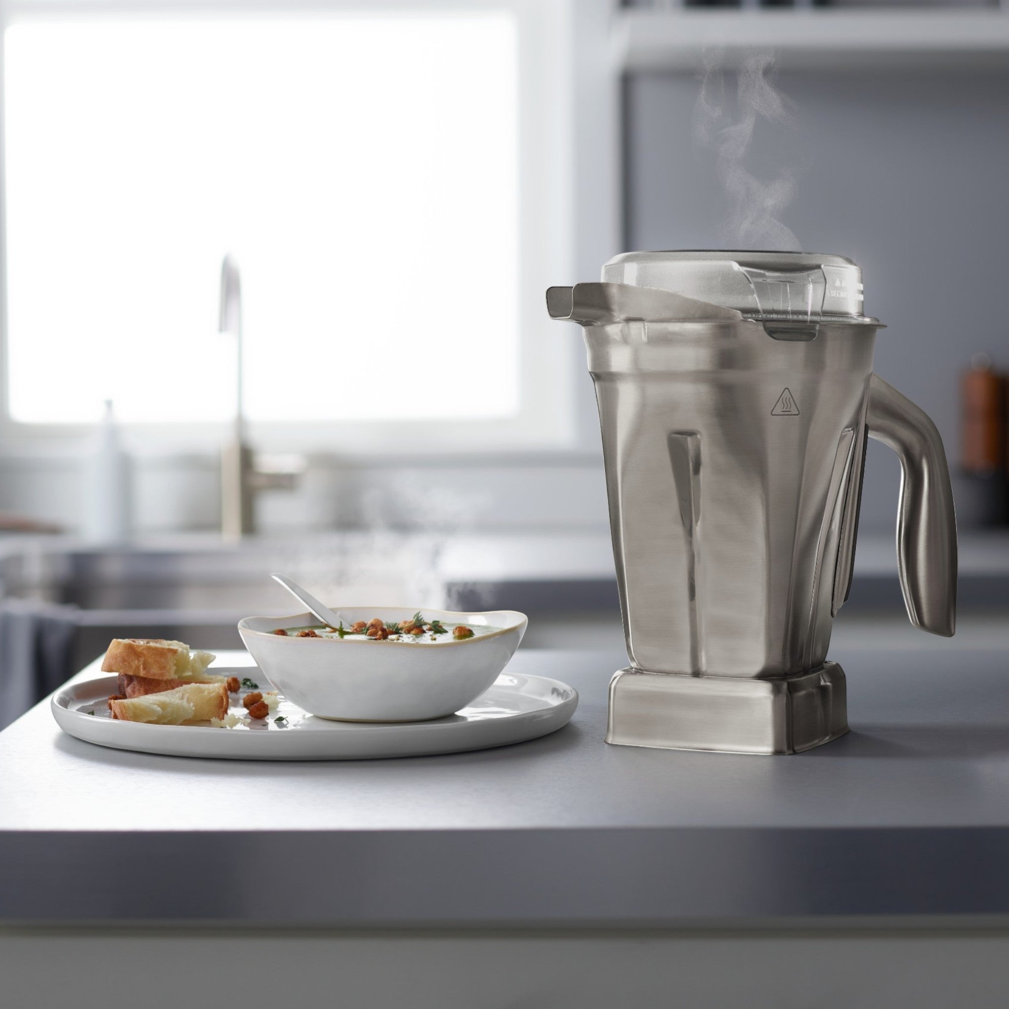 Vitamix 1,4 L Edelstahl-Behälter in der Küche neben servierter Suppe