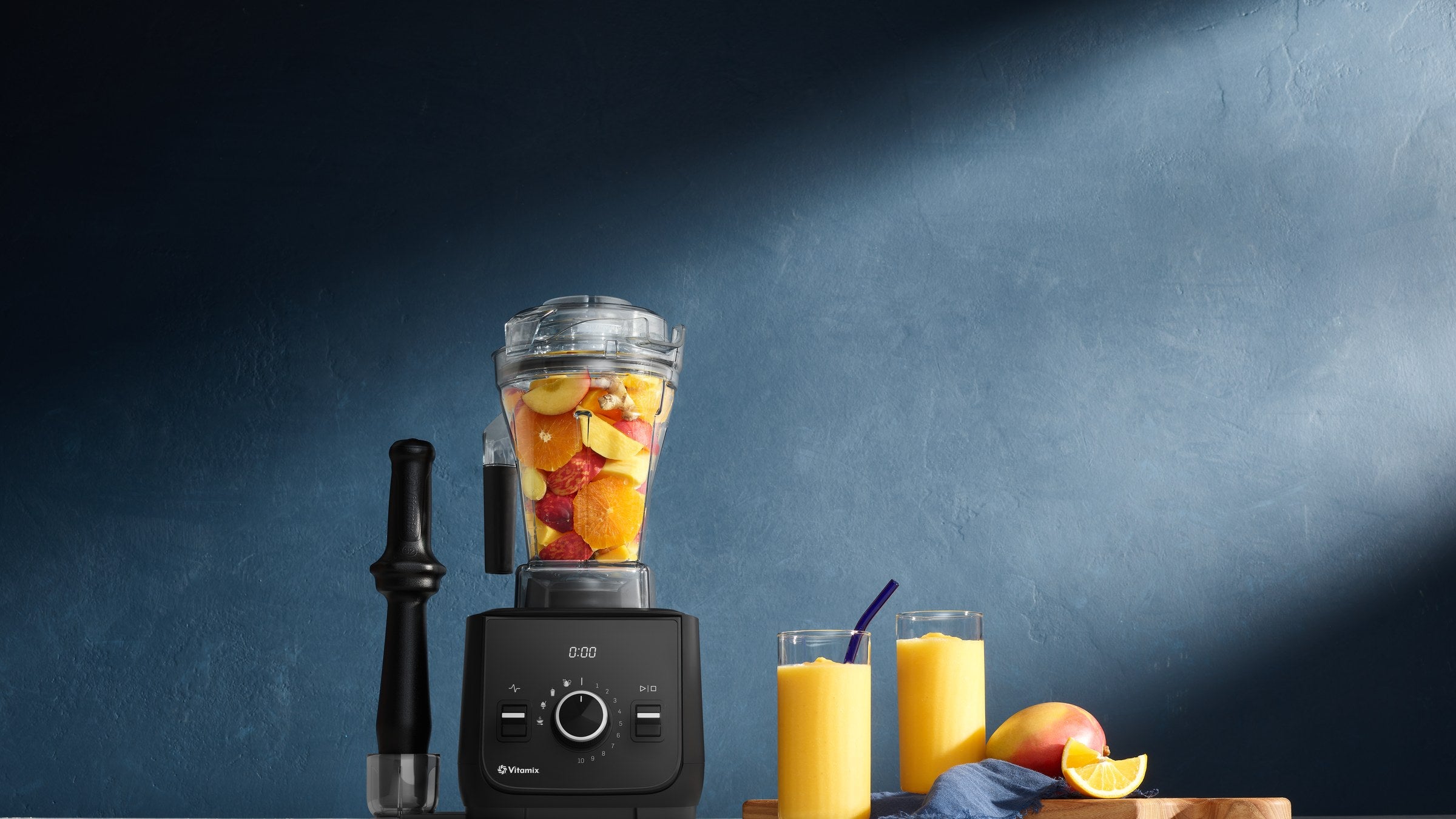 Vitamix Ascent X2 mit Fruechten im Behaelter, daneben zwei Glaeser Orangensaft