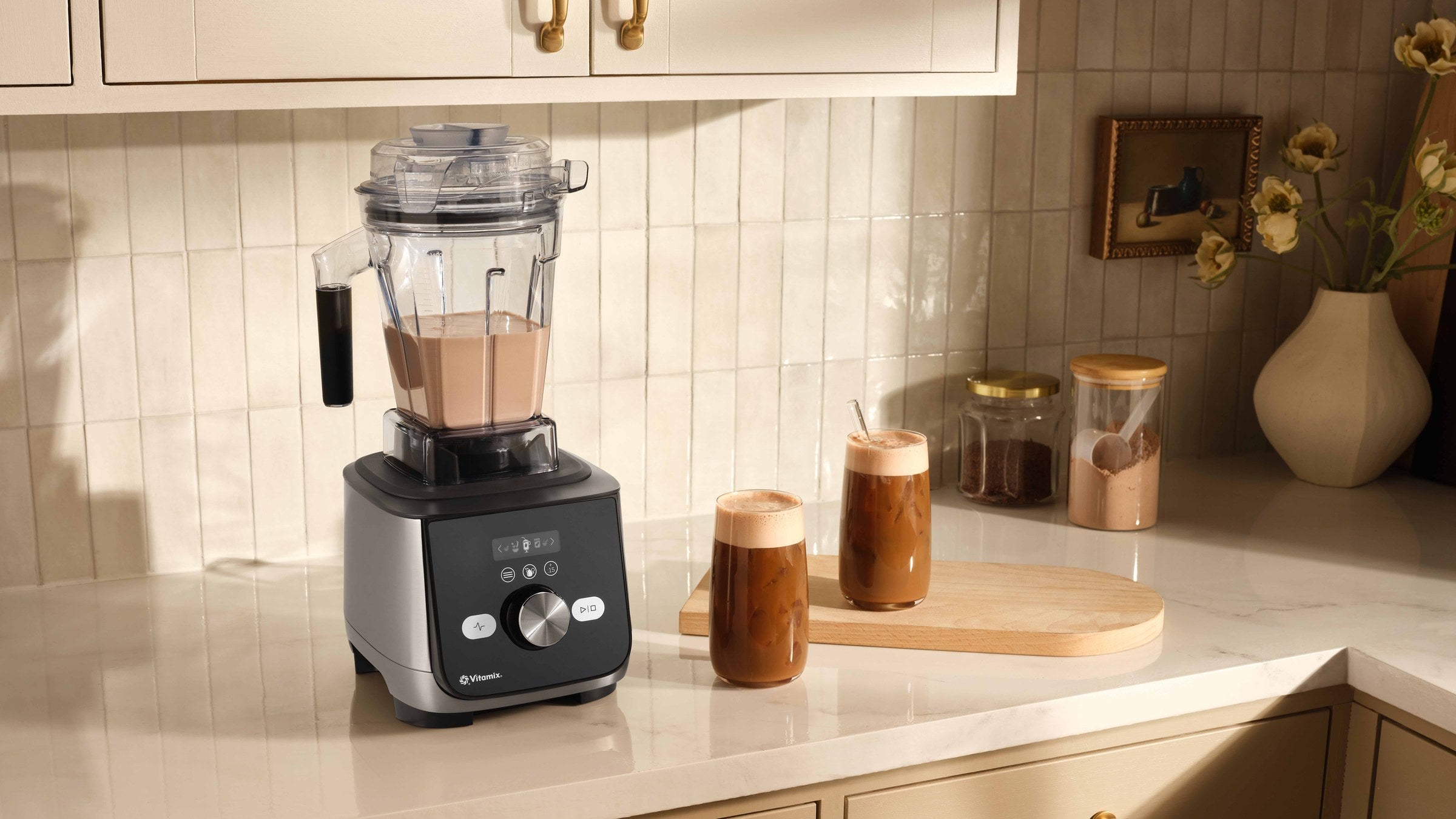 Vitamix Ascent X5 mit Aer-Disc-Behaelter in einer Kueche, daneben Getraenke mit Milchschaum